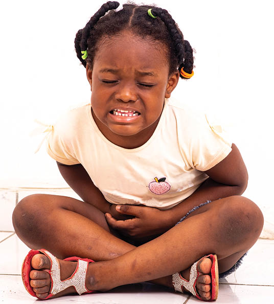 a pretty little girl in jean's panties sitting on the floor at home complaining of stomach aches.