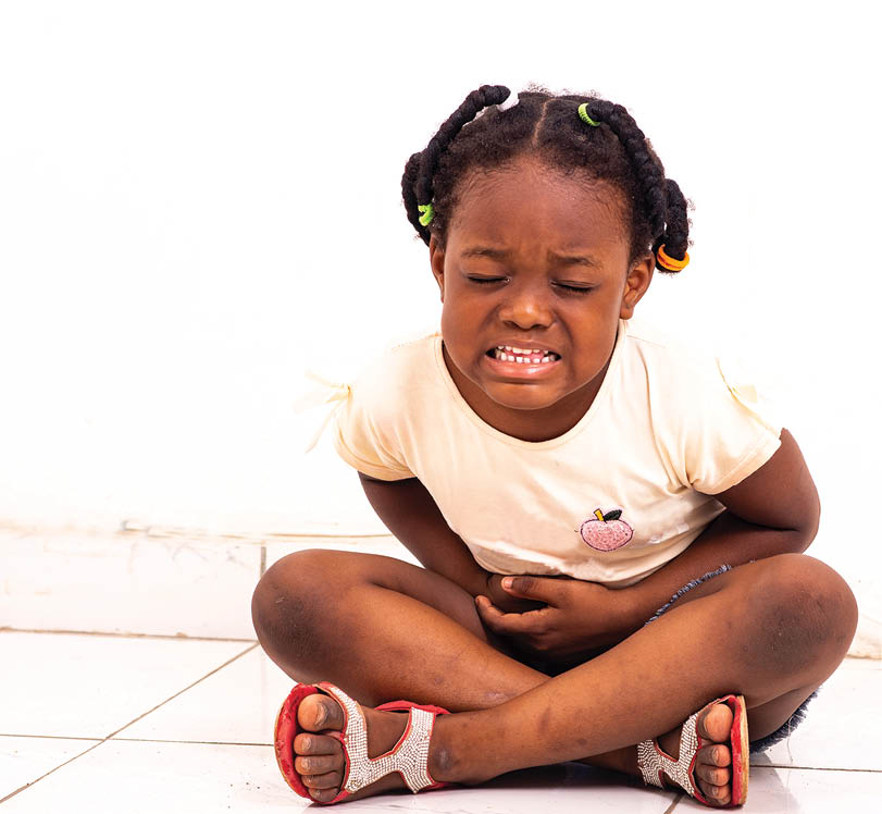 a pretty little girl in jean's panties sitting on the floor at home complaining of stomach aches.