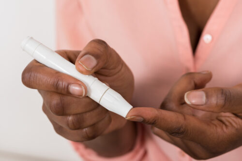 Close-up of person's hand checking blood sugar level with glucometer.