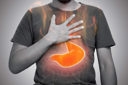 Photograph of a man holding his chest, experiencing gastric reflux