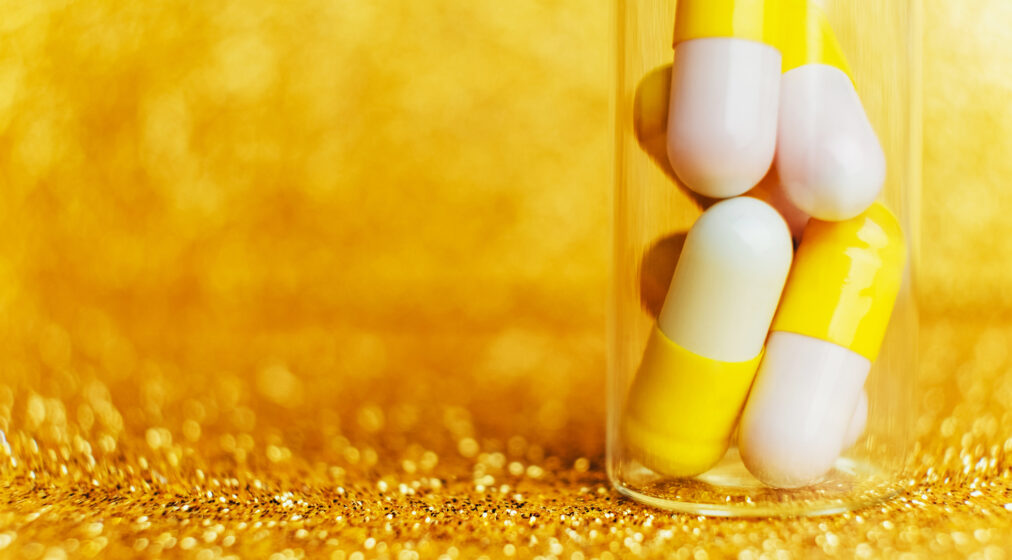 A photograph of a pill bottle with white and orange pills spilling out
